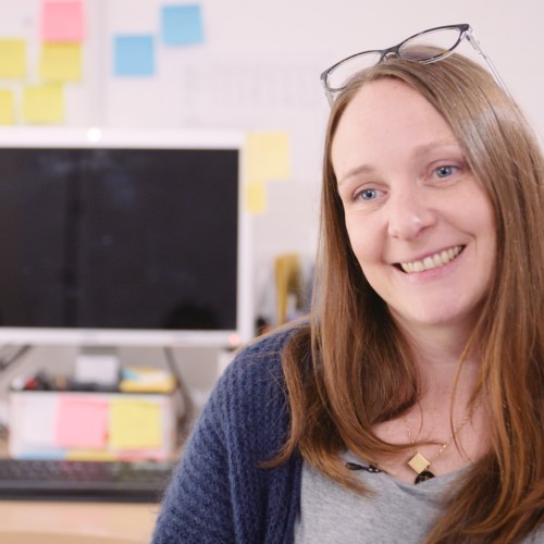 Lucie Hackney sitting at desk with computer screens in background.